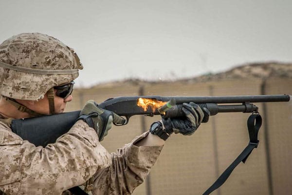 Military shotgun ejecting shell that is on fire