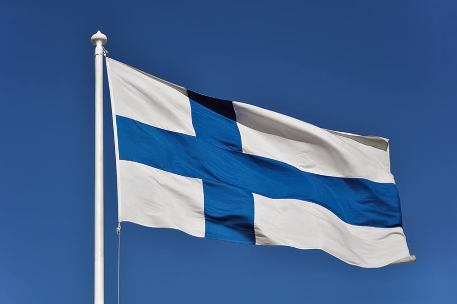 A Finland flag fluttering in the wind under a blue sky.