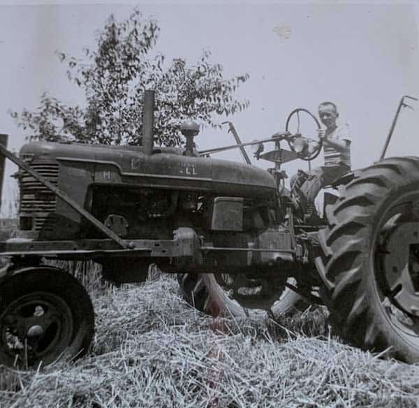 An old black and white photo of a man on a tractor.