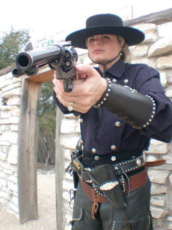 A woman dressed as a cowgirl holding a gun.