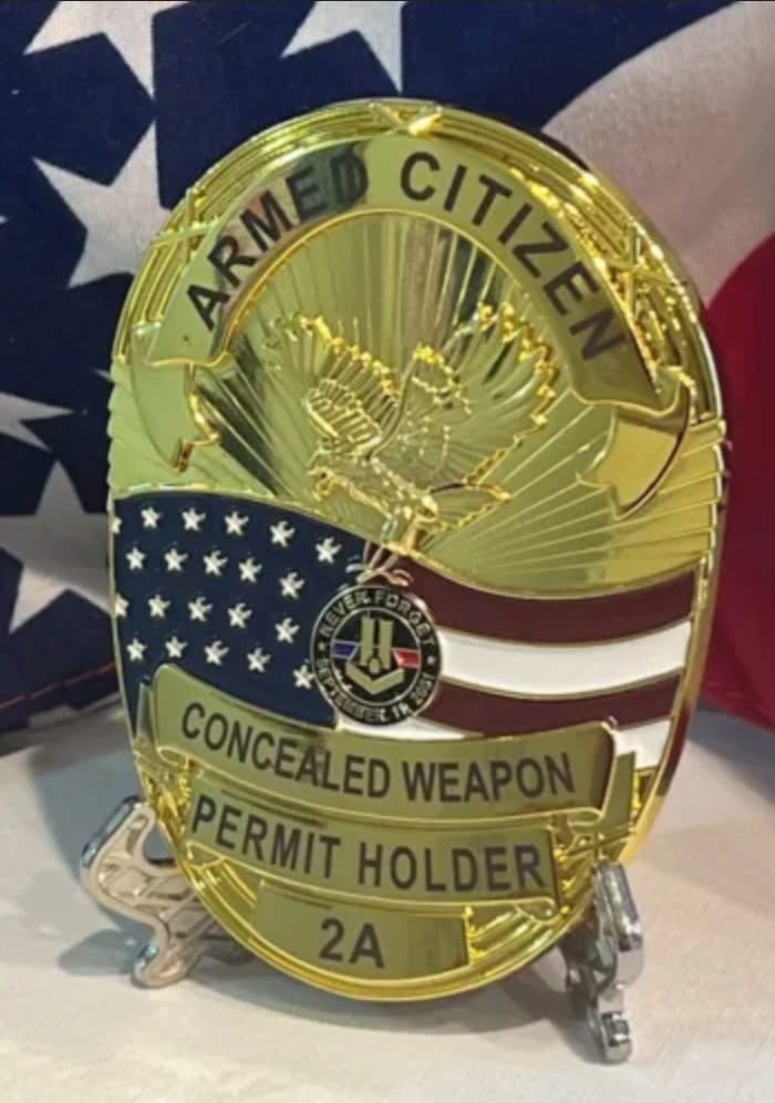 Gold badge with an eagle, u.s. flag, and text reading 'armed citizen' and 'concealed weapon permit holder 2a' on a flag-patterned backdrop.